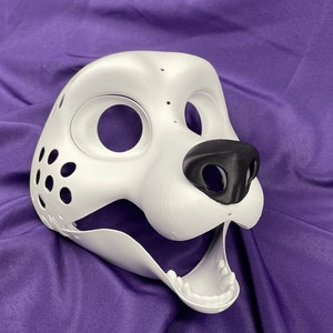 Op de afbeelding: Witte, ongeverfde vachtdiermasker met een zwarte neus en een open mond. Het masker heeft gaten voor de ogen en een gaasgebied aan de zijkant.