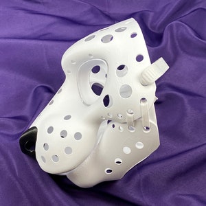 May include: White furry mask with a black nose and many small holes. The mask has white straps on the side.