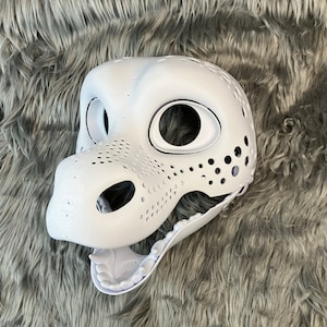 May include: White unpainted furry animal head base with holes for eyes and nose. The mouth is open and has teeth.
