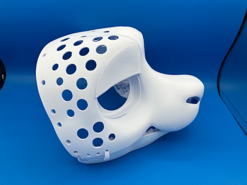 K&ouml;nnte beinhalten: Wei&szlig;e, unbemalte Felltiermaske mit gepunktetem Muster und L&ouml;chern f&uuml;r Augen und Nase. Die Maske besteht aus einem glatten, harten Material und hat eine realistische Form.