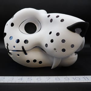 May include: White furry animal mask with black nose and eye holes. The mask is made of a lightweight material and has a textured surface.