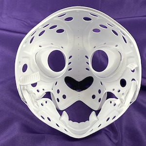 May include: White plastic mask with a detailed design resembling a cat's face. The mask has large eye holes, a small nose, and a wide mouth with teeth.