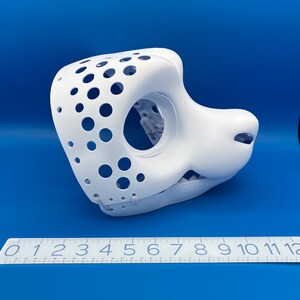 K&ouml;nnte beinhalten: Wei&szlig;e, unfertige Felltiermaske mit ausgeh&ouml;hltem Augen- und Mundbereich. Die Maske hat ein gepunktetes Muster und ist aus hartem Kunststoff.