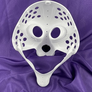 Op de afbeelding: Witte plastic goalie-masker met een gezichtsmasker en een kinband. Het masker heeft veel kleine gaatjes.