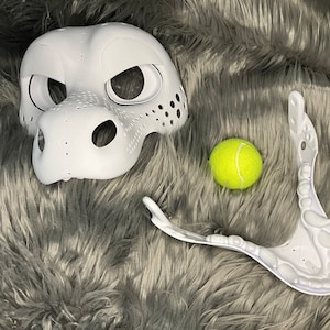 May include: White unfinished furry mask with a textured nose and eye holes. A white plastic jaw piece and a yellow tennis ball are also pictured.