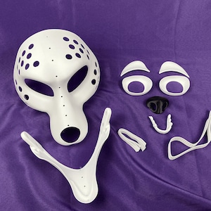 Op de afbeelding: Witte plastic masker met gaten en een aparte set witte plastic gezichtskenmerken, inclusief ogen, neus en mond.