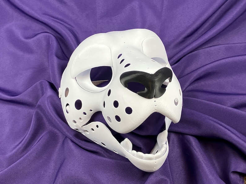 May include: White furry animal mask with black nose and open mouth. The mask has holes for eyes and a textured surface.