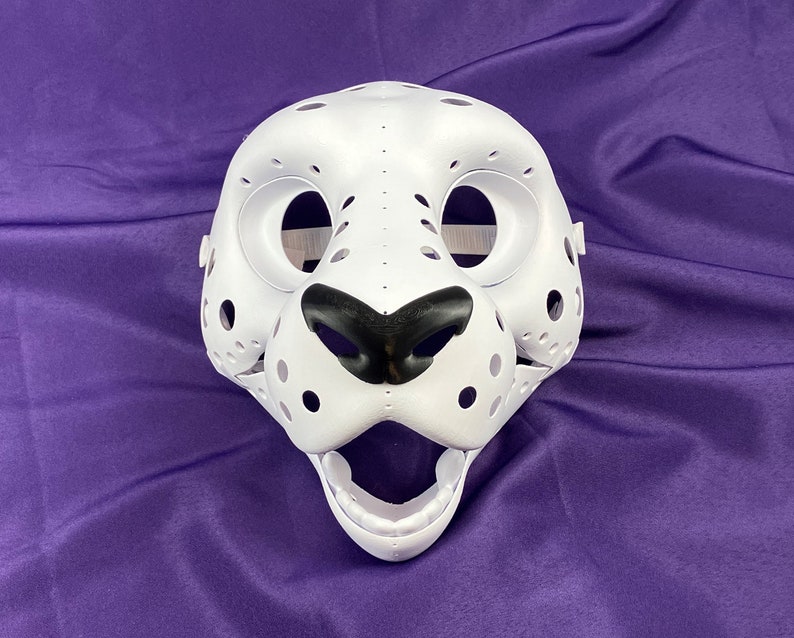 May include: White unfinished furry animal mask with black nose and eye holes. The mask has a textured surface with small holes.