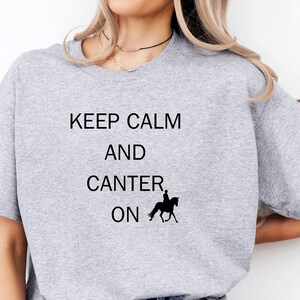 May include: A grey t-shirt with the text "Keep Calm and Canter On" and a silhouette of a person riding a horse.