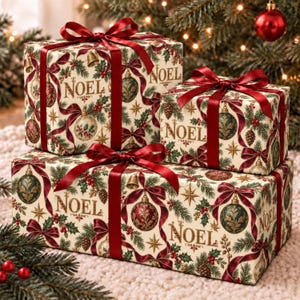 May include: Three rectangular gift boxes wrapped in cream-colored paper featuring a festive pattern of red ribbons, green pine branches, gold stars, pinecones, and ornaments with the word NOEL in gold script, each tied with a deep red satin ribbon.