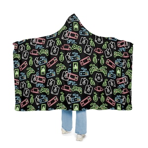 May include: A black hooded blanket with a neon green, pink, and blue pattern of video game controllers, joysticks, and other gaming icons.