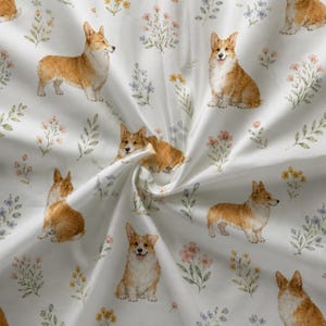 Puede incluir: Una tela blanca con un patrón repetitivo de perros Corgi marrones y blancos en varias posturas, intercalados con pequeñas ilustraciones estilo acuarela de flores silvestres rosas, amarillas y azules y tallos de hojas verdes en la superficie.