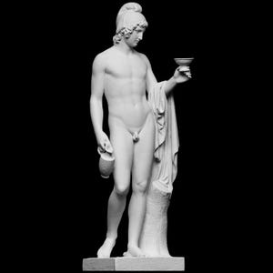 Op de afbeelding: Een witmarmeren beeld van een naakte mannelijke figuur die een kleine kom en een kruik vasthoudt. De figuur draagt een helm en een gedrapeerde doek. Het beeld staat tegen een zwarte achtergrond.