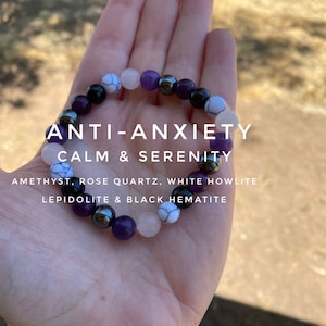 May include: A bracelet made with amethyst, rose quartz, white howlite, lepidolite, and black hematite beads. The bracelet is labeled "ANTI-ANXIETY CALM & SERENITY".