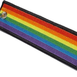 May include: A rainbow-colored key chain with a black border and a silver key ring. The rainbow colors are red, orange, yellow, green, blue, indigo, and violet.