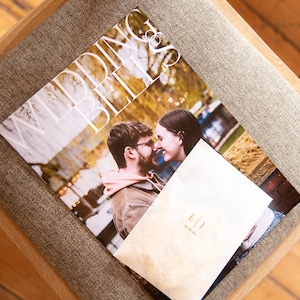 May include: A wedding magazine featuring a couple on the cover, a white envelope with the initials "E & J" and the date "21.04.24" printed in gold.