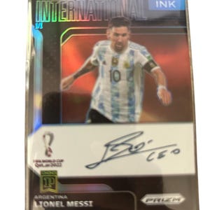 Puede incluir: Una taza de cerámica blanca con un asa negra y el texto "But First, Coffee" en negrita negra. La taza se encuentra sobre un fondo neutro, resaltando su diseño simple.