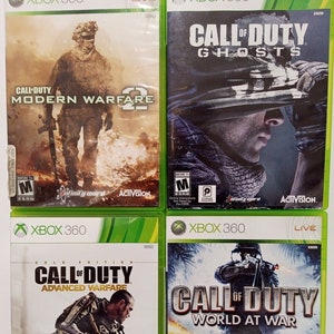 Könnte beinhalten: Vier Xbox 360-Videospielhüllen mit verschiedenen Call of Duty-Spielen. Die Hüllen sind grün und schwarz mit dem Spieltitel und einem Bild eines Soldaten auf der Vorderseite. Die Spiele sind Call of Duty: Modern Warfare 2, Call of Duty: Ghosts, Call of Duty: Advanced Warfare und Call of Duty: World at War.