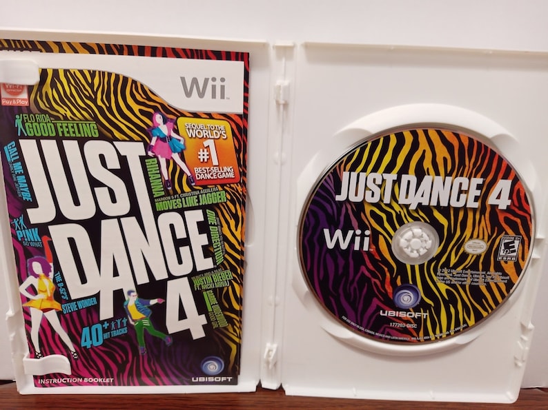May include: Opened Wii game case for Just Dance 4. The cover features the game title in large white letters, with colorful graphics and artist names. The disc inside has the game title and Wii logo.