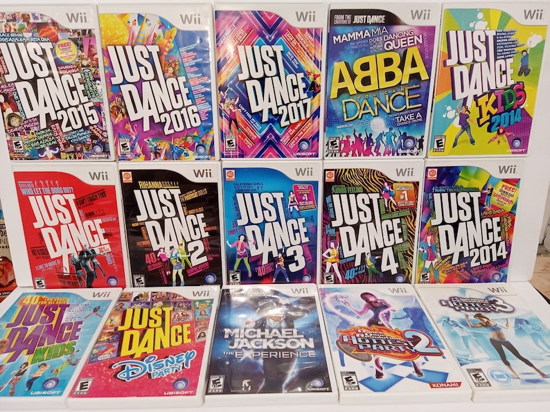 May include: A collection of Wii video game cases, featuring the "Just Dance" series, with titles like "Just Dance 2015", "Just Dance 2016", and "Just Dance 2017". Other titles include "ABBA Dance" and "Michael Jackson: The Experience".