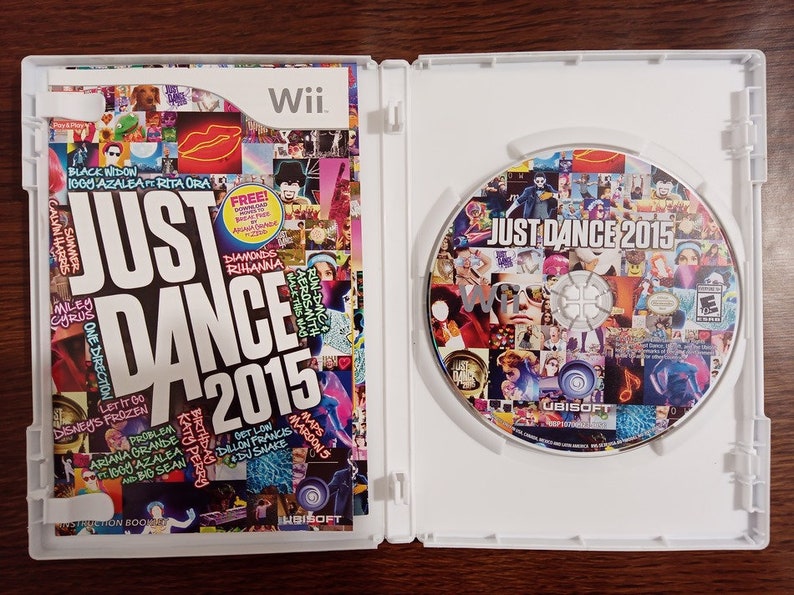May include: Opened Wii game case for "Just Dance 2015." The cover art features a collage of images and the game title. The disc inside also displays the game title and a collage of images. The case is white.