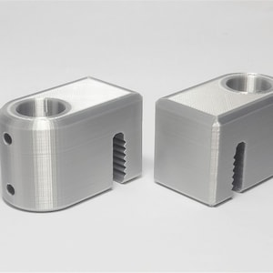 May include: Two gray 3D printed plastic clamps with a threaded hole and a toothed edge.