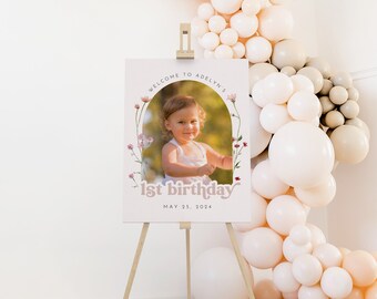 Puede incluir: Un cartel de bienvenida rosa y blanco con un arco floral y una foto de una niña pequeña. El cartel dice "Bienvenido a Adelyn's 1er cumpleaños 25 de mayo de 2024".