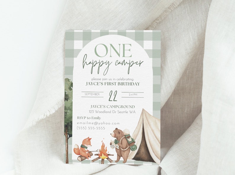 Op de afbeelding: Een groene en witte ruitjespatroon uitnodiging met een witte cirkel en de tekst "ONE happy camper" in groene schrijfletters. De uitnodiging is voor Jayce's eerste verjaardag en bevat de datum, tijd en locatie van het feest. De uitnodiging bevat ook een aquarel illustratie van een vos en een beer die kamperen.