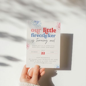 May include: A colourful invitation with a red, white and blue firework design. The text reads "our little firecracker is turning one!" and includes details for a first birthday party. The party is on Saturday, 22nd July from 1-3 PM. The address is 123 Juniper Lane, Richmond VA 12345. RSVP to Emily at (555) 555-5555 or emailme@yahoo.com.