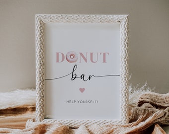 Könnte beinhalten: Ein weiß gerahmtes Schild mit dem Text "DONUT bar" in rosa Schrift mit einer rosa Donut-Grafik und dem Text "HELP YOURSELF!" in schwarzer Schrift.