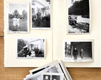 May include: An open scrapbook with cream-colored pages featuring five black and white vintage photographs. The photos show people in outdoor settings, a house, and a waterfall. Handwritten dates include AUG 1942, 1945, and MAR 1939 below the images.