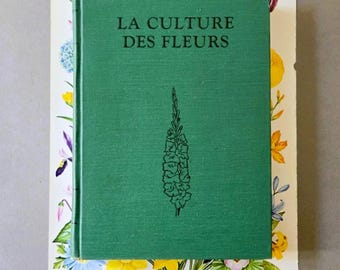 Op de afbeelding: Een groen gebonden boek met de titel LA CULTURE DES FLEURS en een zwarte lijntekening van een bloem op de voorkant. Het boek ligt op een rechthoekig vel papier met een kleurrijke botanische illustratie van verschillende bloemen.
