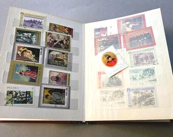 Op de afbeelding: Een open postzegelalbum met twee pagina's vol met diverse postzegels uit Polen. De postzegels tonen uiteenlopende historische, artistieke en culturele afbeeldingen, waaronder portretten, landschappen en scènes, met de tekst POLSKA zichtbaar.