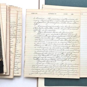 Peut inclure: Un journal vintage avec une couverture noire texturée et des bords cousus d'or, présentant des pages vieillies couleur crème remplies de texte manuscrit en cursive française. Les pages ouvertes affichent des en-têtes datés et lignés.