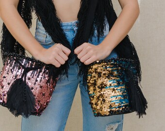 May include: Two sequined bucket bags with black tassels. The bag on the left is pink and black, and the bag on the right is blue, gold, and black.