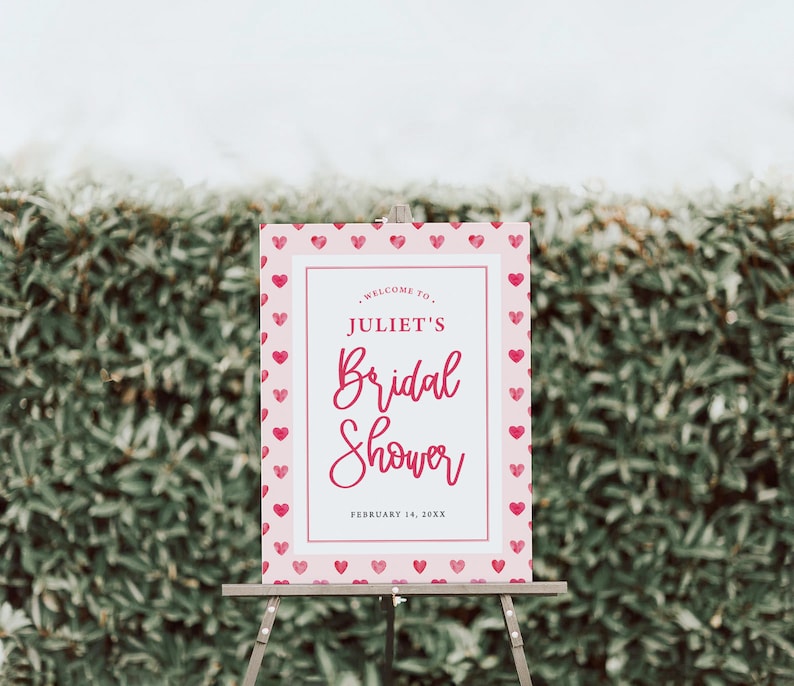 K&ouml;nnte beinhalten: Ein rosa-wei&szlig;es Schild f&uuml;r eine Brautparty mit einem Herzmuster als Rand. Auf dem Schild steht "Willkommen zur Brautparty von Juliet, 14. Februar 20XX".