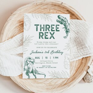 May include: A white invitation with green text and illustrations of dinosaurs. The text reads "Three Rex Stomp chomp and roar Let's party like a dinosaur! Join us to celebrate Jackson's 3rd Birthday Aug 15 1PM 14 Fossil Drive Barrington, Rhode Island RSVP to Mia by August 1 at 123.456.7890"