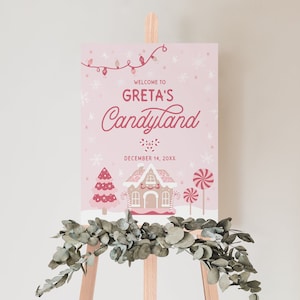 Op de afbeelding: Een roze welkomstbord met een peperkoekhuis, snoepstokken en een kerstboom. Het bord zegt "Welkom bij Greta's Candyland" en "14 december 20XX".