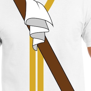 Può includere: Una maglietta bianca con un design marrone e oro. Il design presenta un panno bianco avvolto attorno a un bastone marrone, con due strisce dorate dietro.