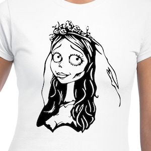 May include: White t-shirt featuring a black and white illustration of a cartoon bride with long hair, a floral crown, and a veil. The bride has large eyes and a subtle smile. The design is centered on the shirt.