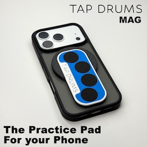 May include: A black phone case with a white camera module and a blue and white practice pad attached. The practice pad has four black circles and the text "TAP DRUMS". The text "TAP DRUMS MAG" is at the top.