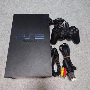 May include: A black PlayStation 2 console with a black controller, cables, and AV leads.