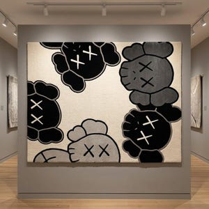A square hand-tufted pop art character wool rug in black, grey, and cream displayed vertically as textile wall art under gallery spot lighting, showcasing the symmetrical placement of the cartoon character heads.