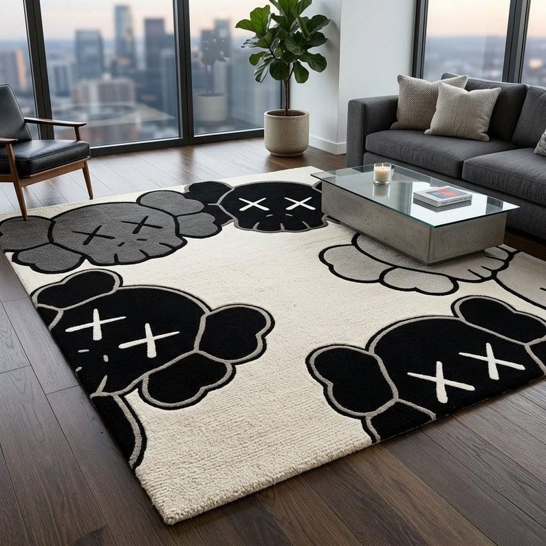 ​A large rectangular greyscale pop-art character wool area rug styled under a wooden coffee table, surrounded by a grey sofa and a brown leather lounge chair in a warm, wood-paneled mid-century modern living room.