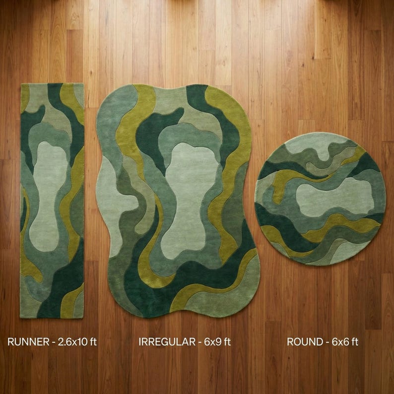Organic modern hand-tufted wool rug in layered green abstract shapes with sculptural edges, styled in a warm minimalist living room.