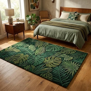 May include: A rectangular green rug with a tropical leaf design. The rug showcases varying shades of green, creating a 3D effect. The rug is placed on a wooden floor in a bedroom setting.