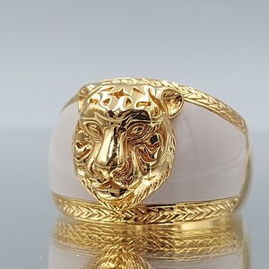 Puede incluir: Un anillo de oro con una banda de esmalte blanco y un diseño detallado de cabeza de tigre.