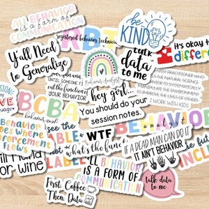 May include: A collection of colorful stickers with various phrases and quotes. The stickers feature text such as "Inclusion is my love language," "It's okay to be different," and "Talk data to me." The stickers are on a light brown surface.