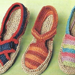 May include: Three pairs of handmade crochet sandals in various colours. One pair features a navy blue and red design, another has orange stripes, and the third showcases a rainbow of pastel colours. All are crafted with a beige base.