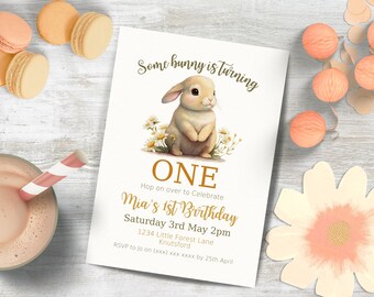 Puede incluir: Una tarjeta de invitación blanca con una linda ilustración de un conejito de dibujos animados. El texto en la tarjeta dice: "Some bunny is turning ONE. Hop on over to celebrate Mia's 1st Birthday. Saturday 3rd May 2pm. 1234 Little Forest Lane, Knutsford. RSVP to jo on (xxx) xxx xxxx by 25th April."